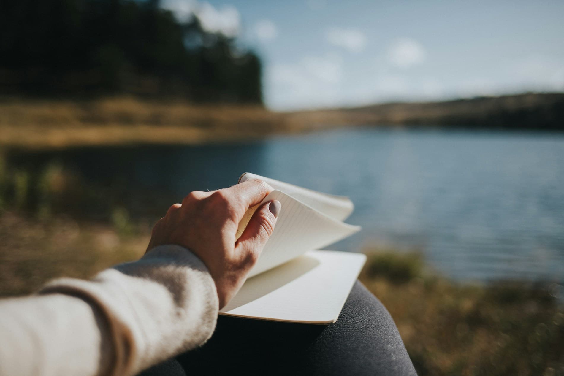 A teen journaling outdoors by a calm lake